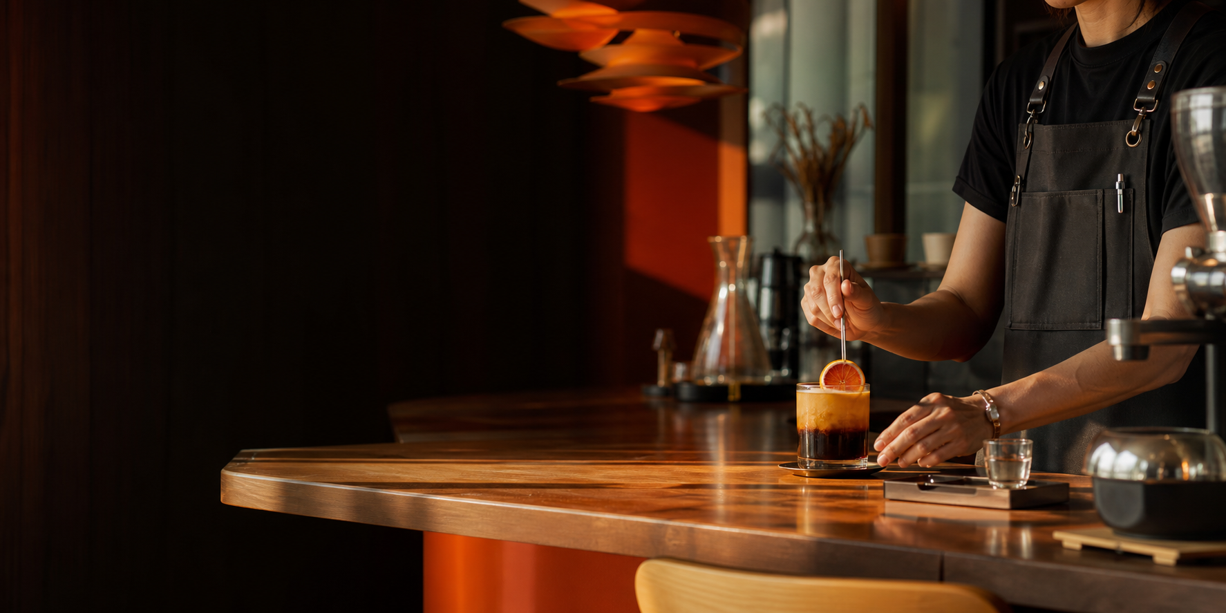 Barista finishing a drink at a warm timber counter